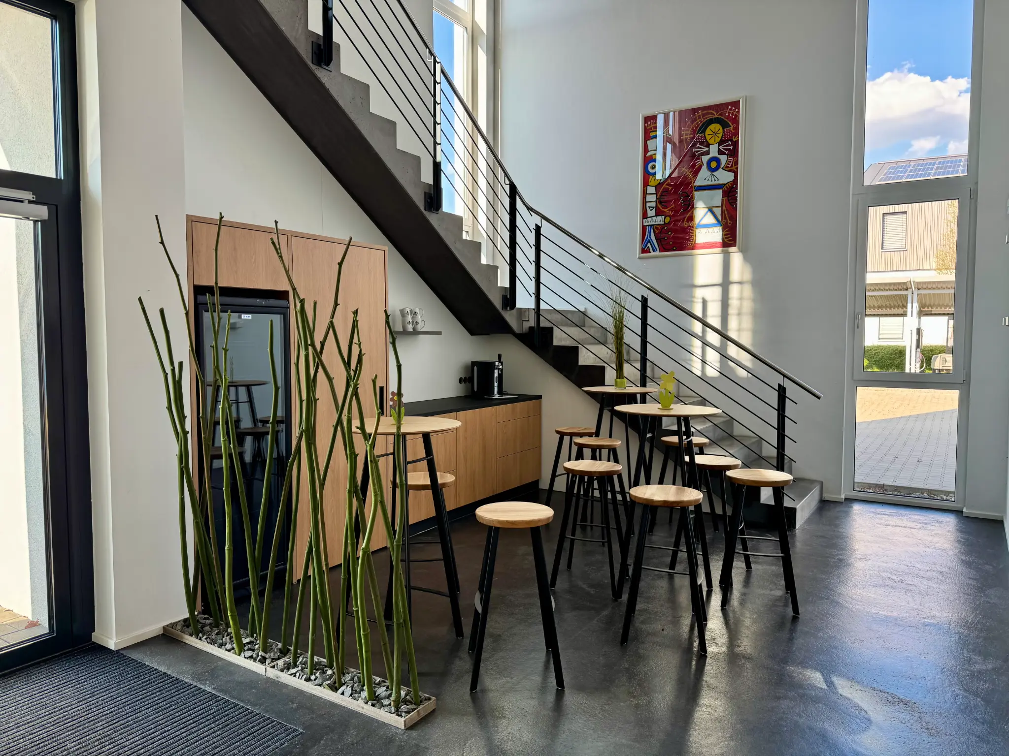 Lounge at HSG Innovation HUB with standing tables and stools beneath the staircase